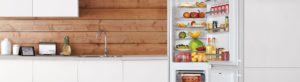 A kitchen set featuring a fridge freezer complete with food and drink