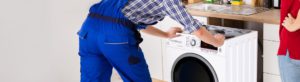 A kitchen fitter installing a washing machine within a kitchen set